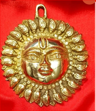 Gold pendant with face design on a red background