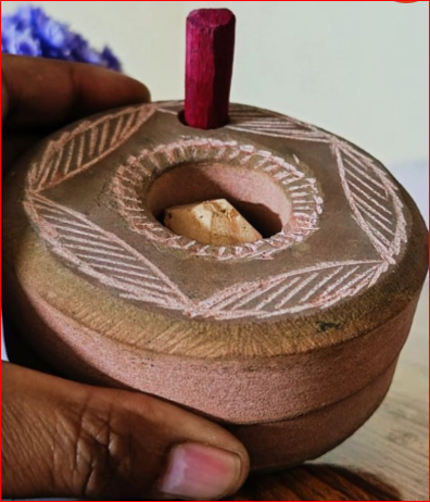 Ceramic incense burner with decorative patterns held by a hand.
